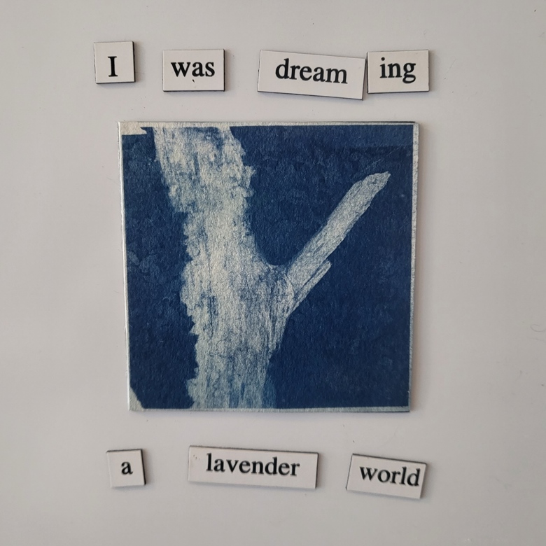 A cyanotype (blue photo) of a log in a field of plants, surrounded by magnet poetry which reads: "I was dreaming a lavender world."